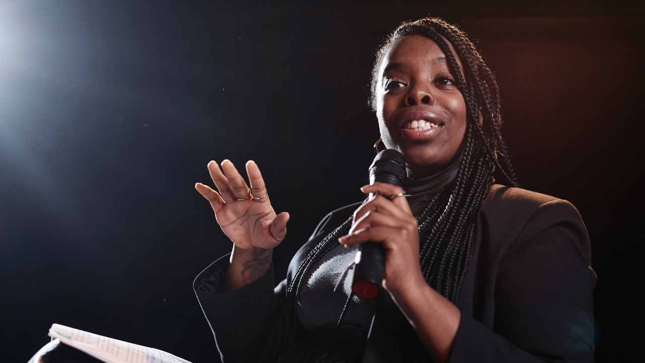 Confident woman speaking to an audience, leading a professional discussion or presentation.